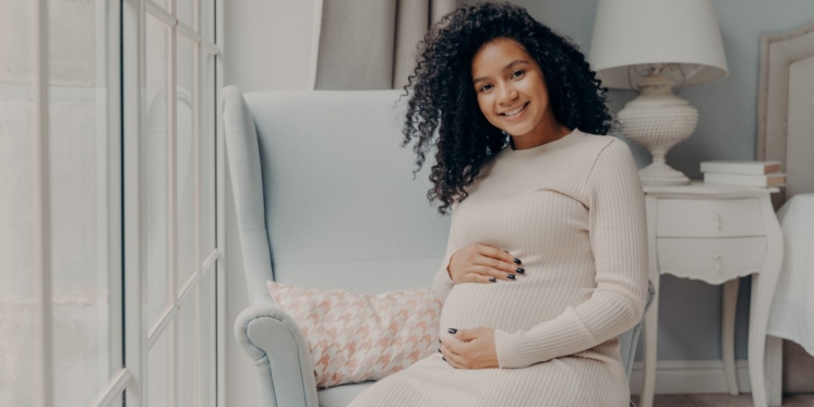 Pregnant women holding her belly while smiling.