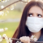 Woman holding hay fever tablets next to blossoming tree