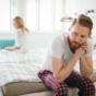 sad couple sat on edge of bed