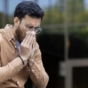 man sitting on bench blowing nose