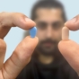 man holding two pills between fingers and thumbs