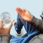 man holding pill and glass of water