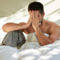man sitting in bed with head in hands