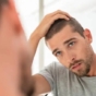 man checking hairline in mirror