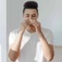 man sneezing into tissue