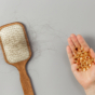 brush with loose hair and hand with vitamins