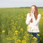 Woman sneezing in a field of flowers