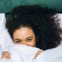 woman hiding behind bed sheet
