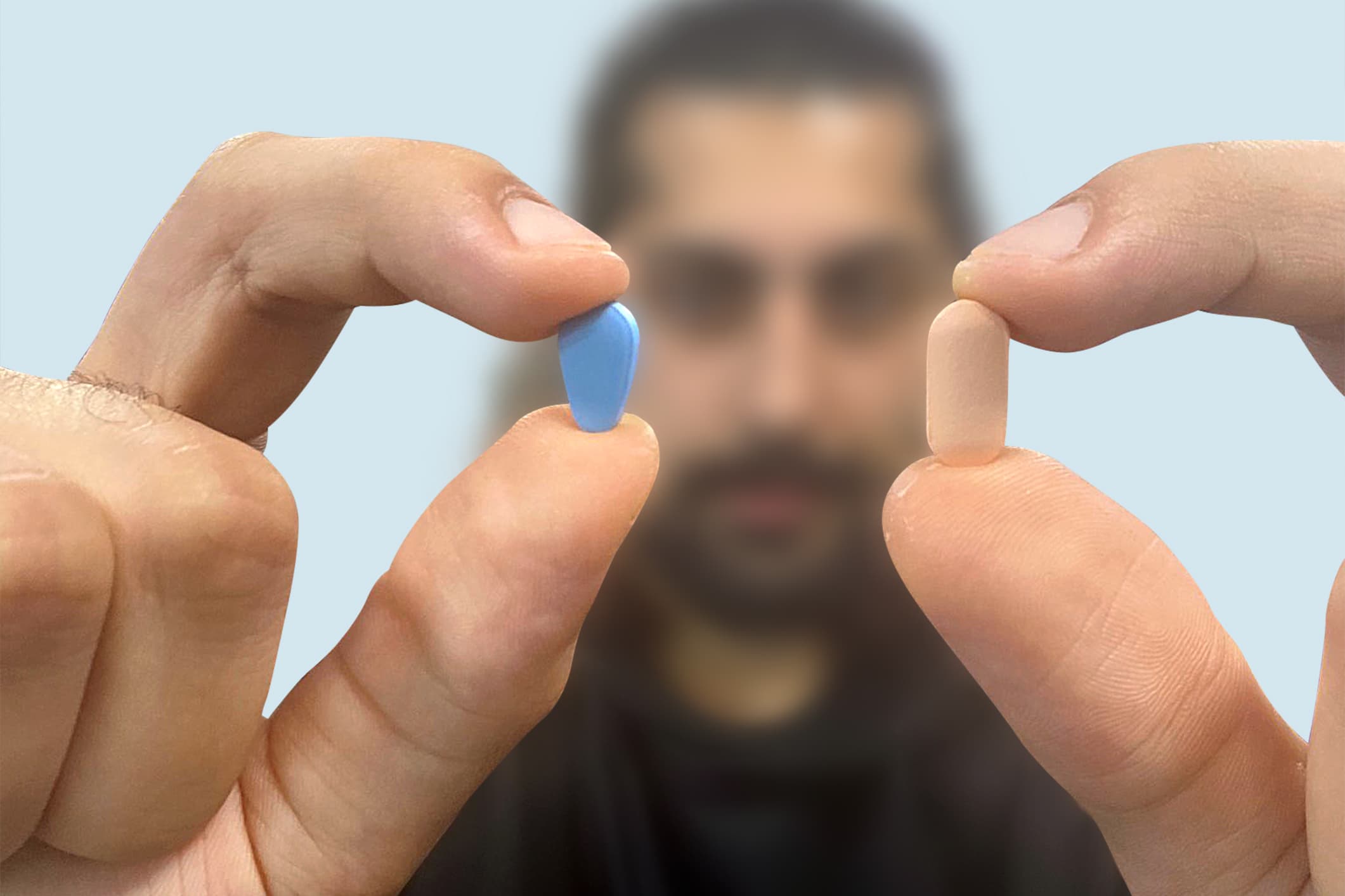 A man holding a Viagra tablet and a Cialis tablet