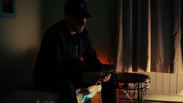 A man sitting in a dark room, on his phone