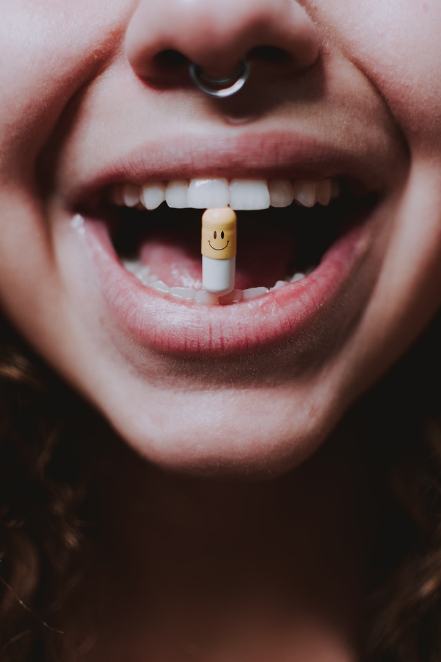 Woman smiling with tablet in her mouth