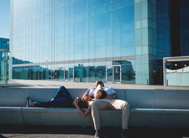 Man sleeping on a bench and woman resting on his place