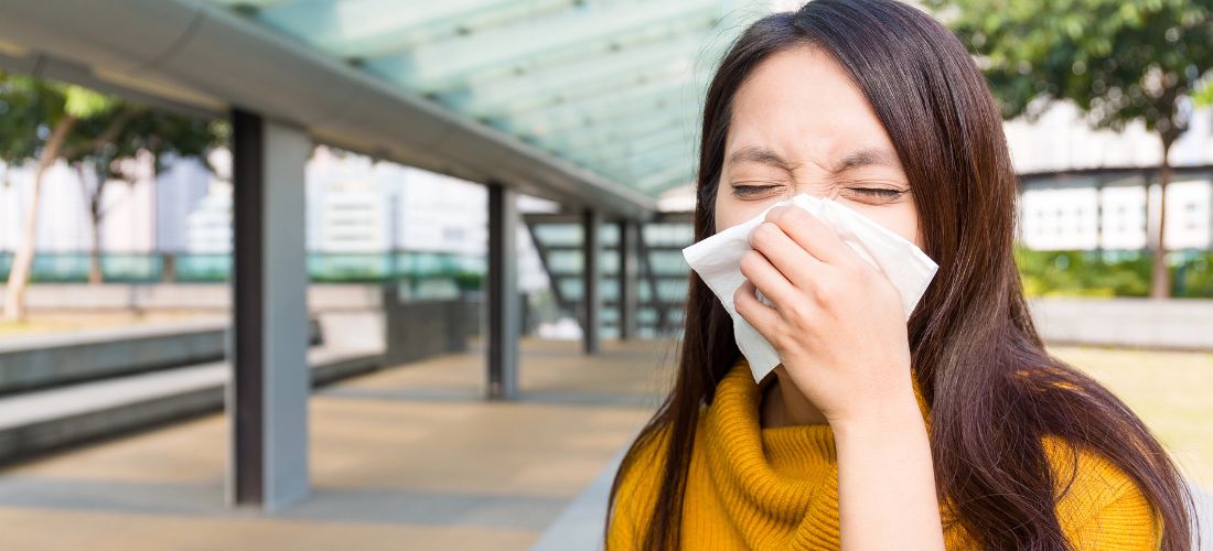 Woman blowing her nose outdoors