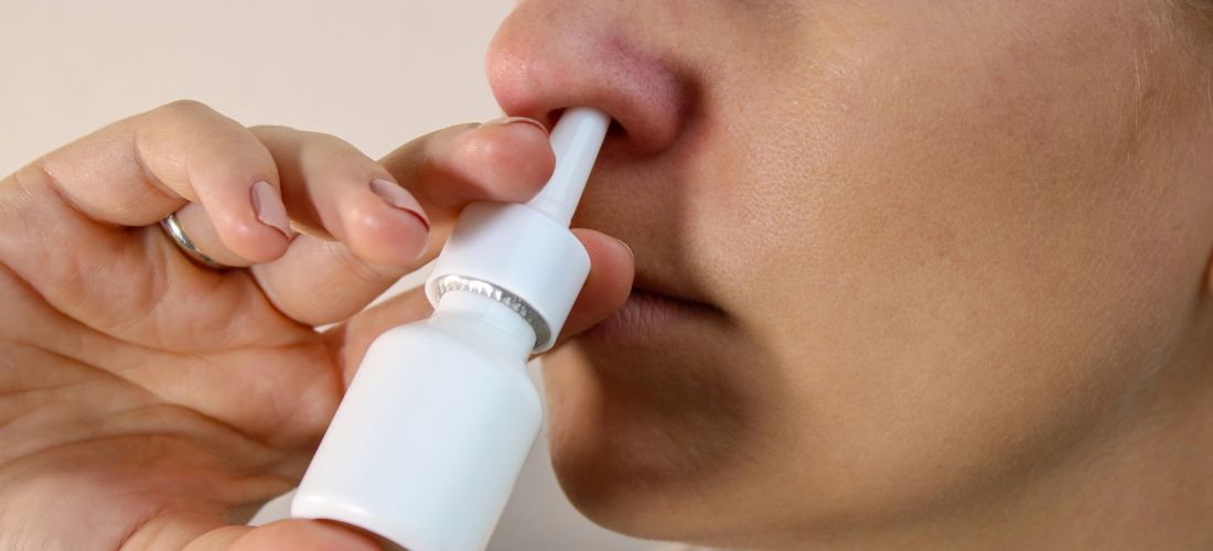 Close up of woman using nasal spray