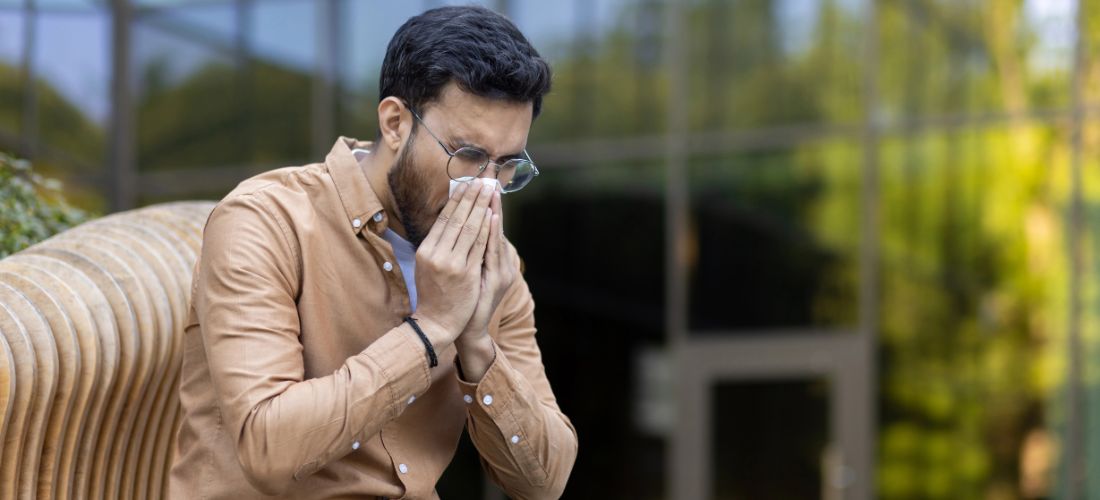 Man sitting on bench blowing nose
