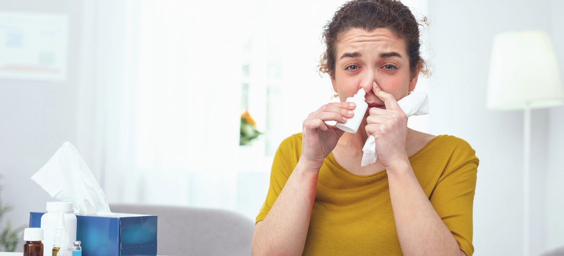 Woman using nasal spray and looking at the camera