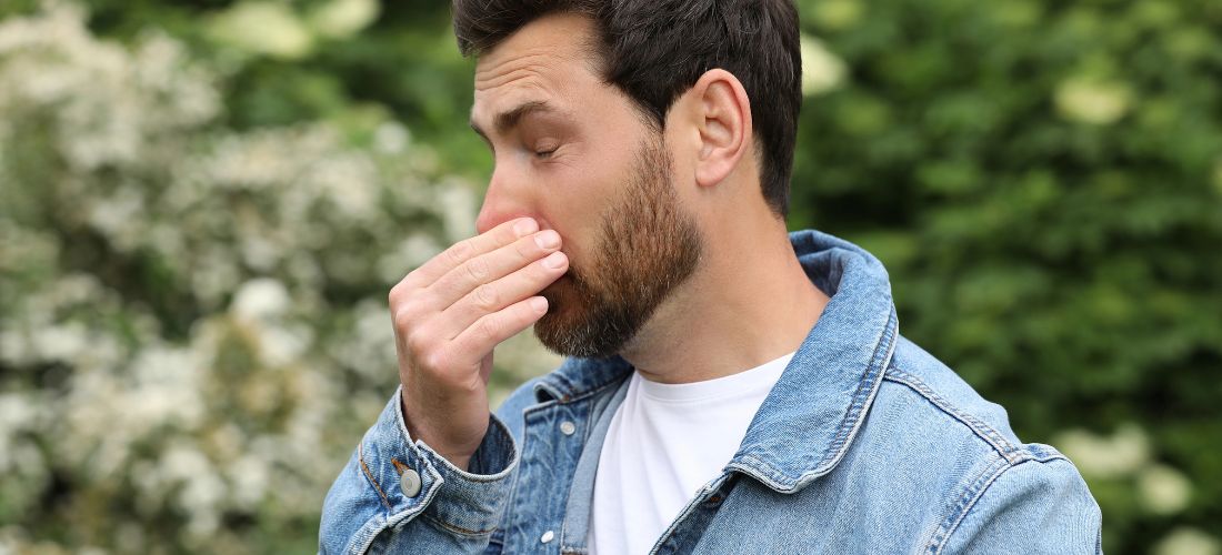 Man struggling with hay fever outdoors