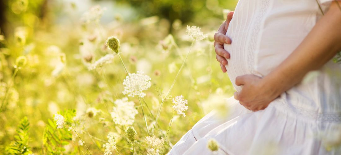 Pregnant woman kneeling in wildflower field