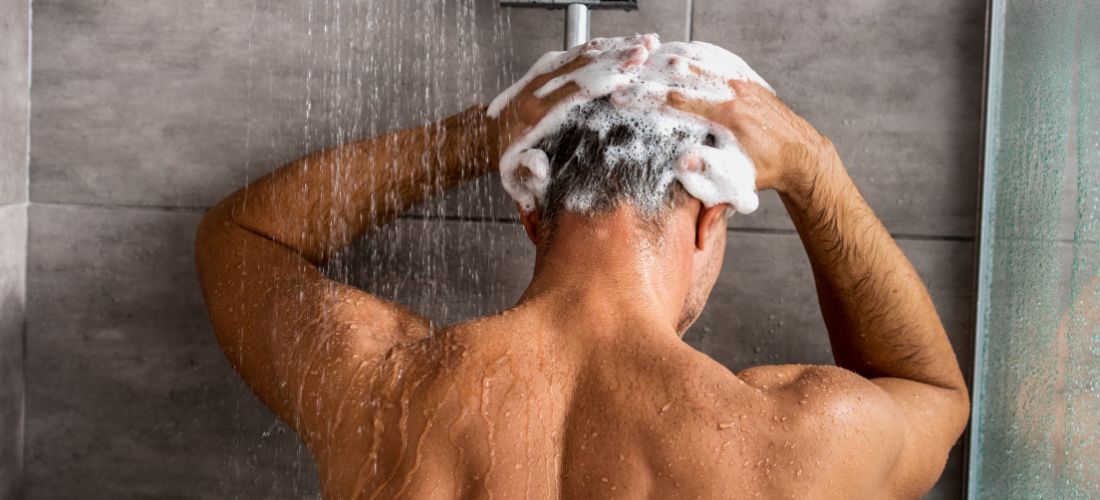 Rear view of man washing his hair in the shower