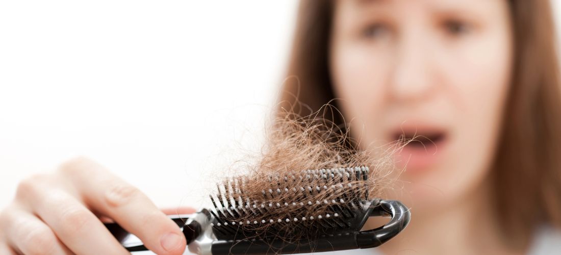 Woman noticing hair loss in hair brush