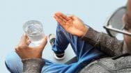 a man about to swallow a finasteride pill with water