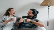 Man and woman sitting on a sofa drinking coffee