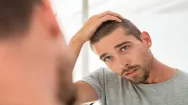 Man looking at his hairline in a mirror