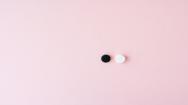A black pill and a white pill on pink background