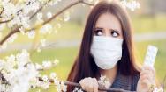 Woman holding hayfever tablets next to blossoming tree