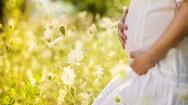 Pregnant woman kneeling in wildflower field